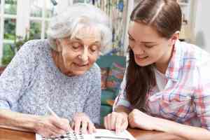 © highwaystarz - Fotolia.com Junges Mädchen löst Kreuzworträtsel mit älterer Dame